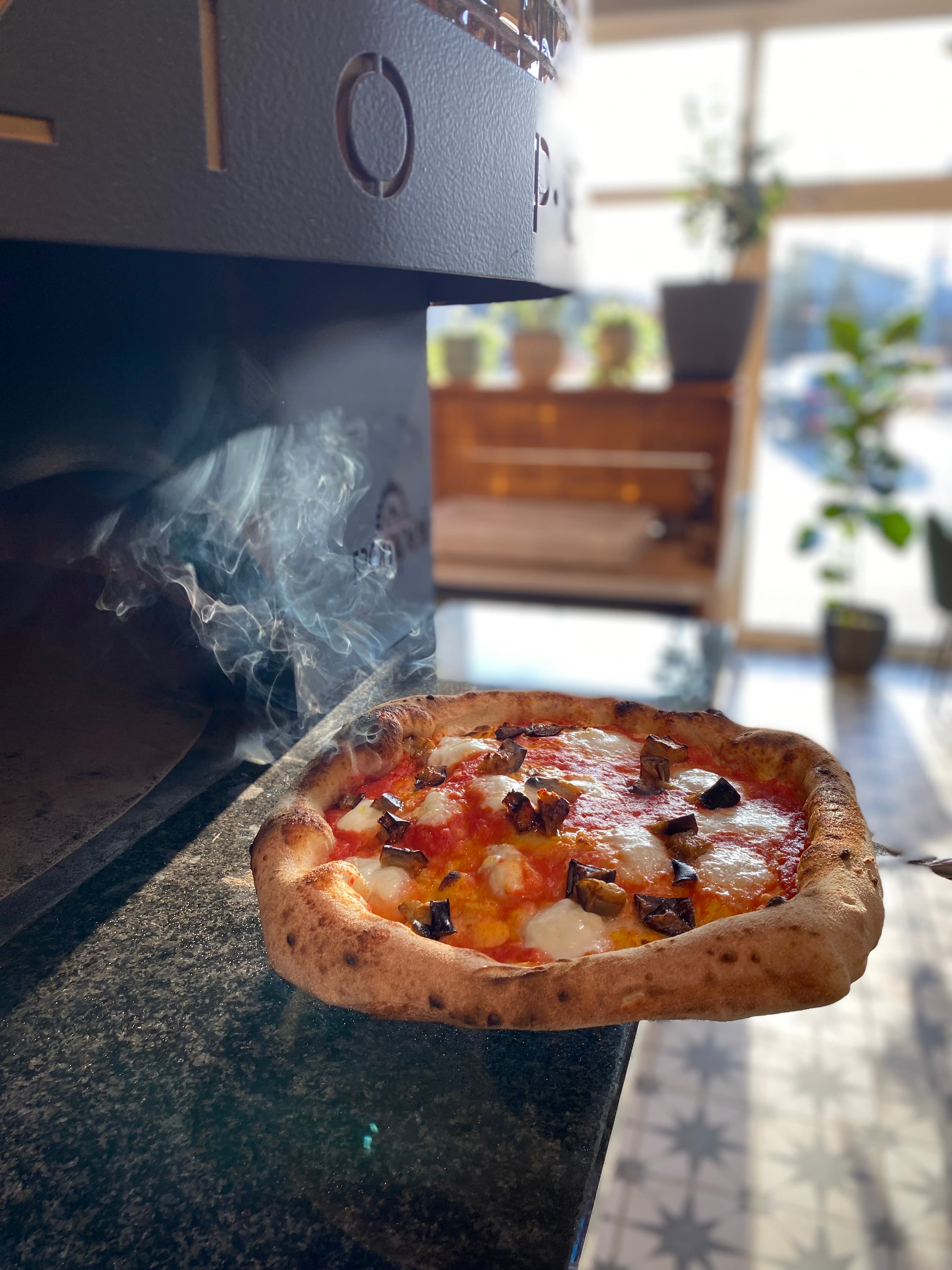 Pizza na łopacie wyjmowana z pieca, w kłębach pary